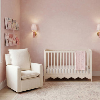 Nursery featuring a wooden crib, a rocking chair, pink walls, and a wall-mounted shelf with magazines.