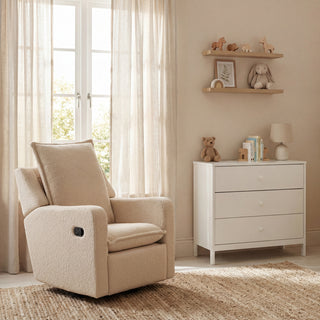 Recliner chair next to white dresser, with toys on shelves and light curtains covering windows.