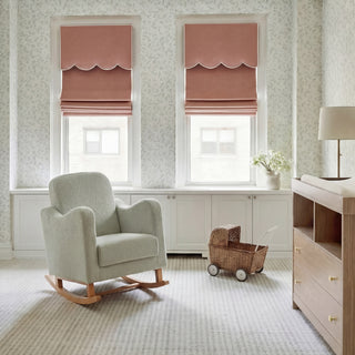 Rocking chair in a light room with two windows, a wooden cabinet, and a toy cart on the floor.